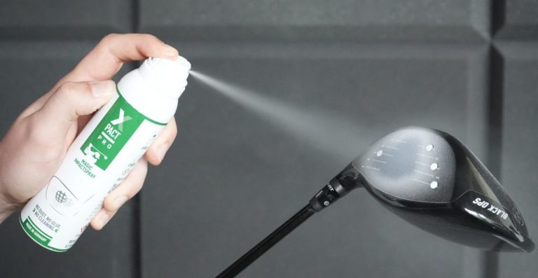Image of a person spraying white spray on a golf club face.
