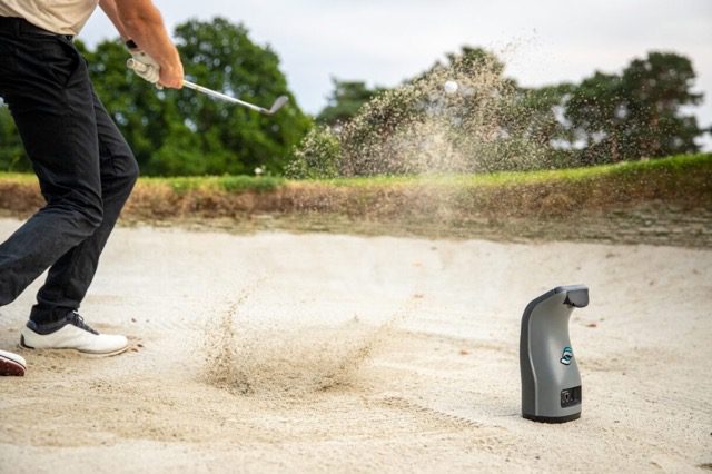Image of a male golfer hitting a wedge in a sand bunker on a golf course.