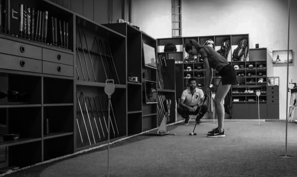 woman putting on a indoor golf green in front of a fitter