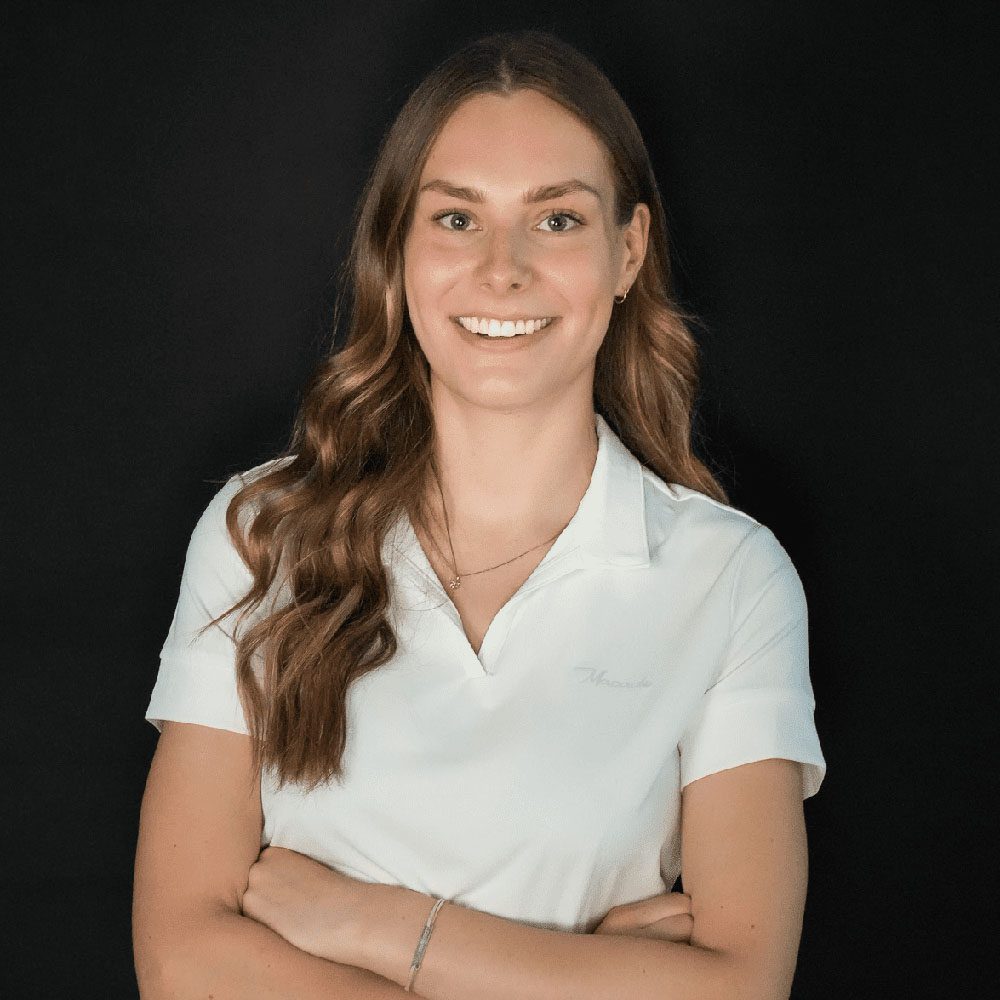 photo displaying a woman wearing a white polo smiling into the camera