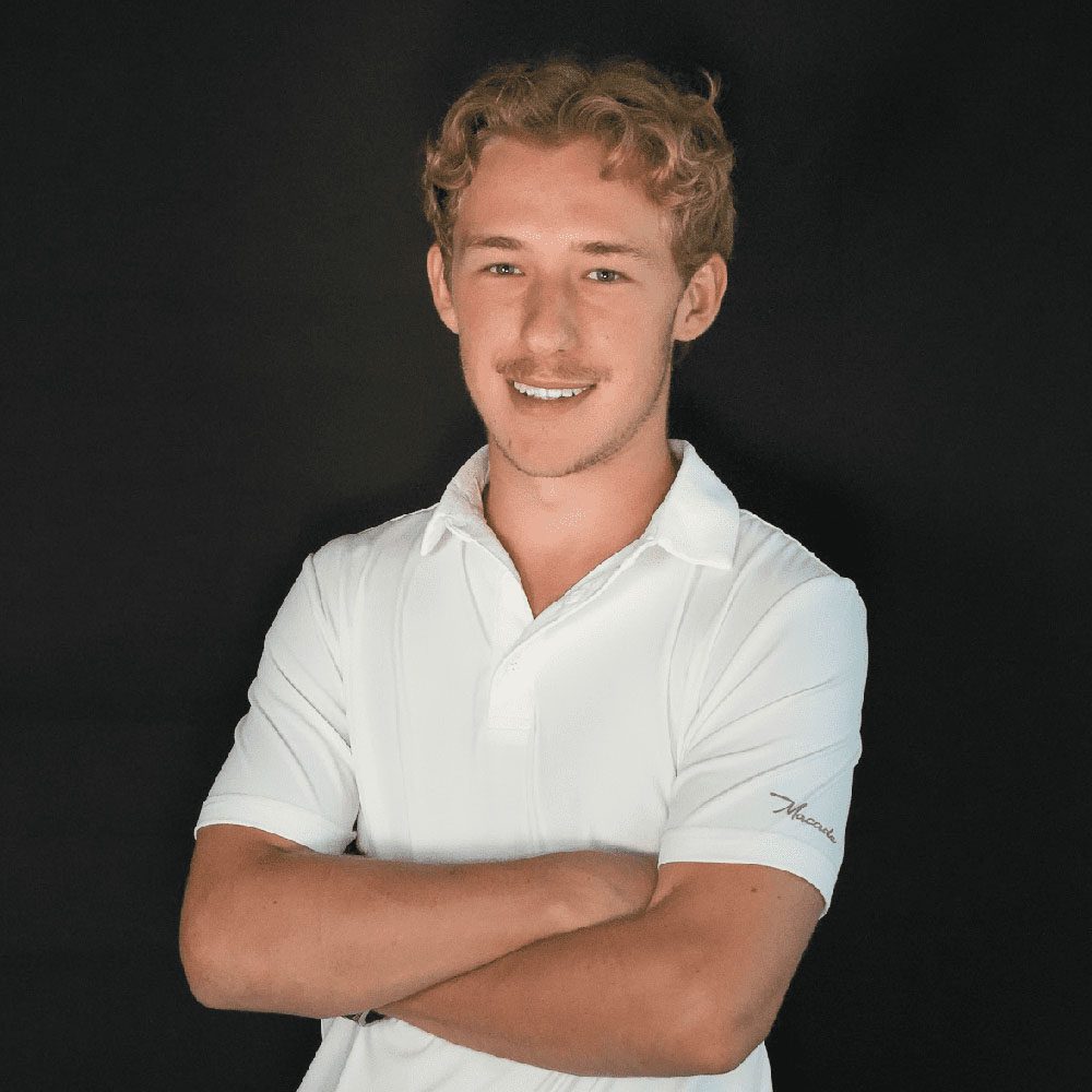 photo displaying a man wearing a white polo smiling into the camera