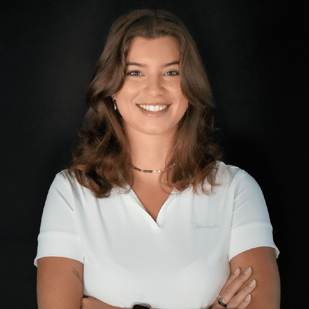 photo displaying a woman wearing a white polo smiling into the camera