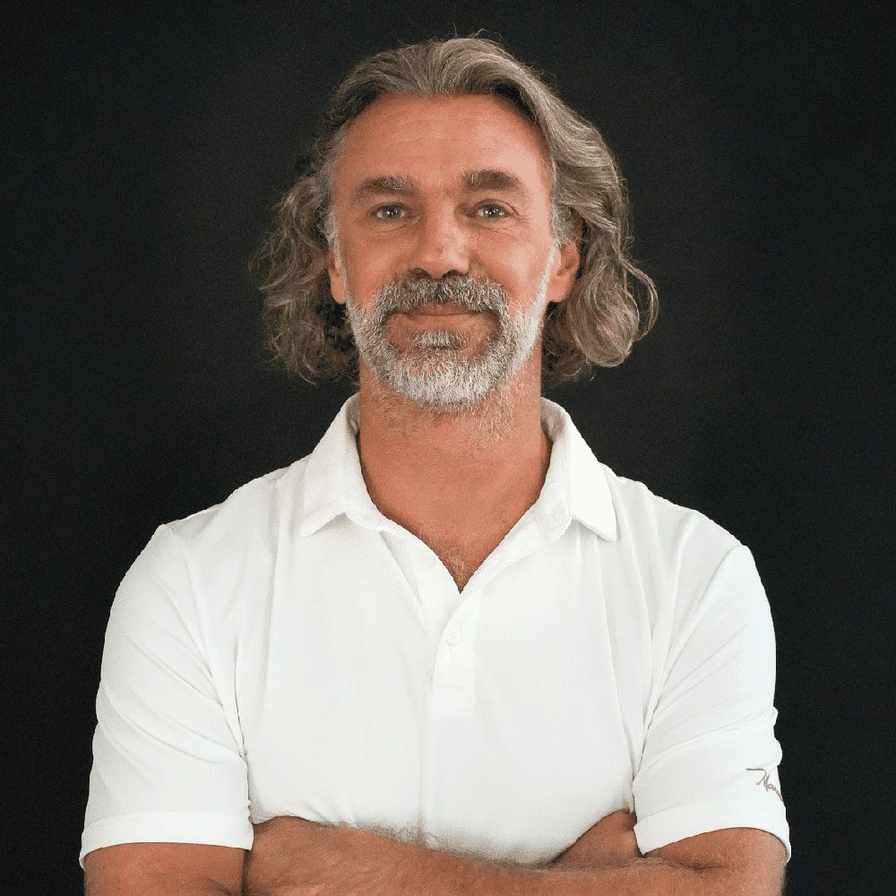 photo displaying a man wearing a white polo smiling into the camera