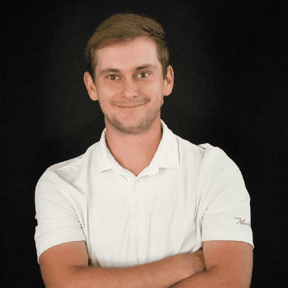 photo displaying a man wearing a white polo smiling into the camera