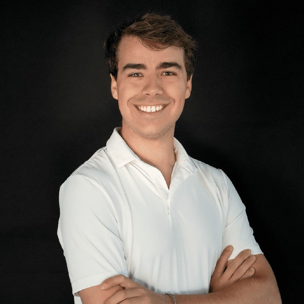 photo displaying a man wearing a white polo smiling into the camera