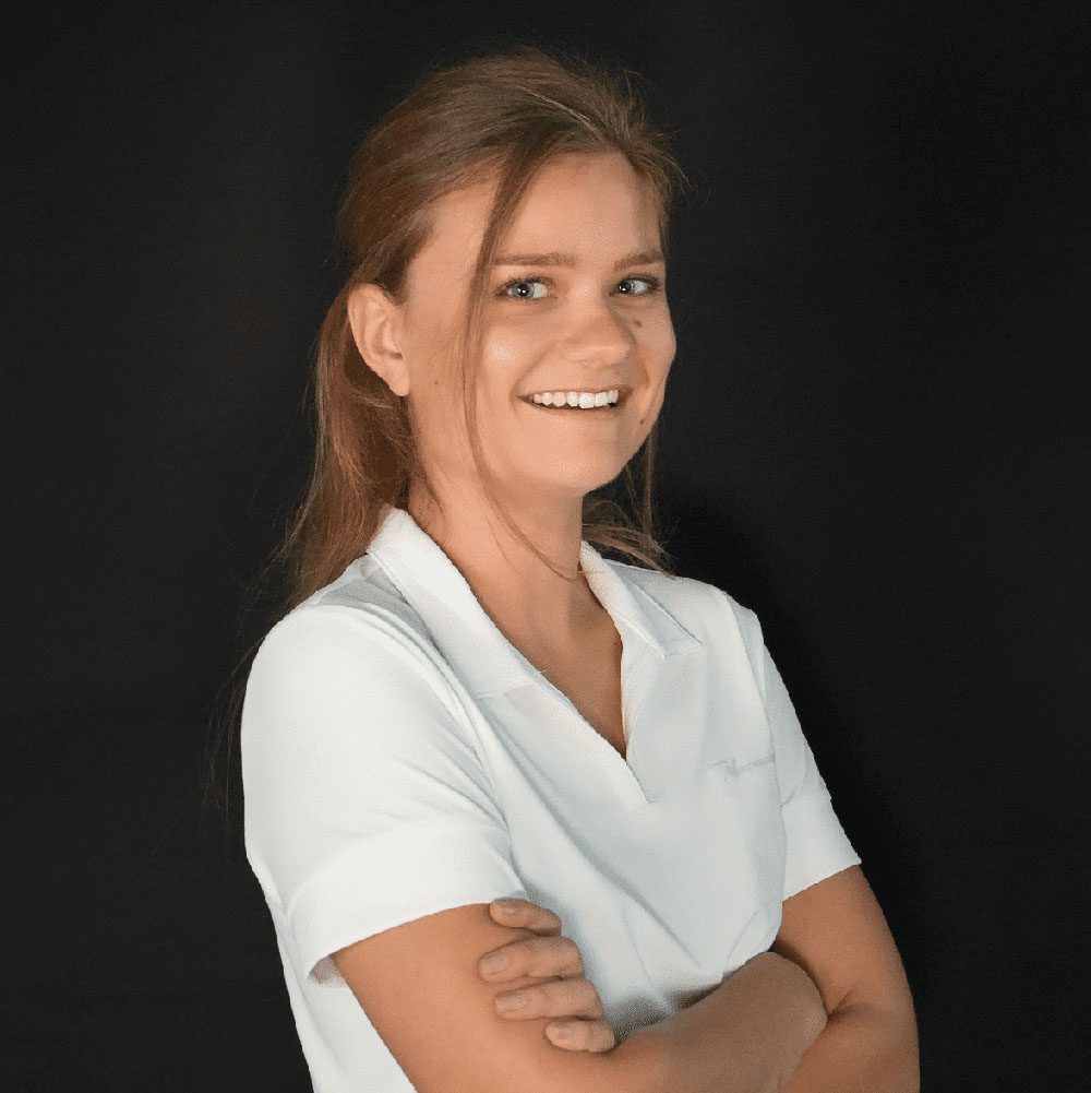 photo displaying a woman wearing a white polo smiling into the camera