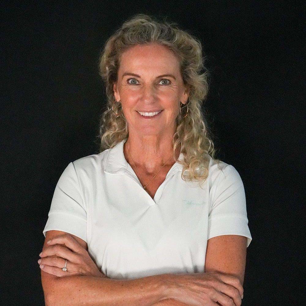 photo displaying a woman wearing a white polo smiling into the camera