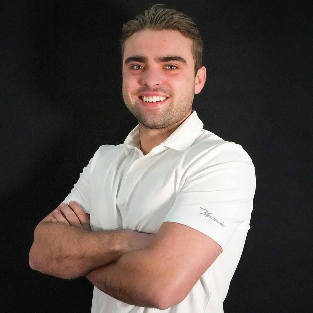 Image of a young man wearing a white polo smiling into the camera.