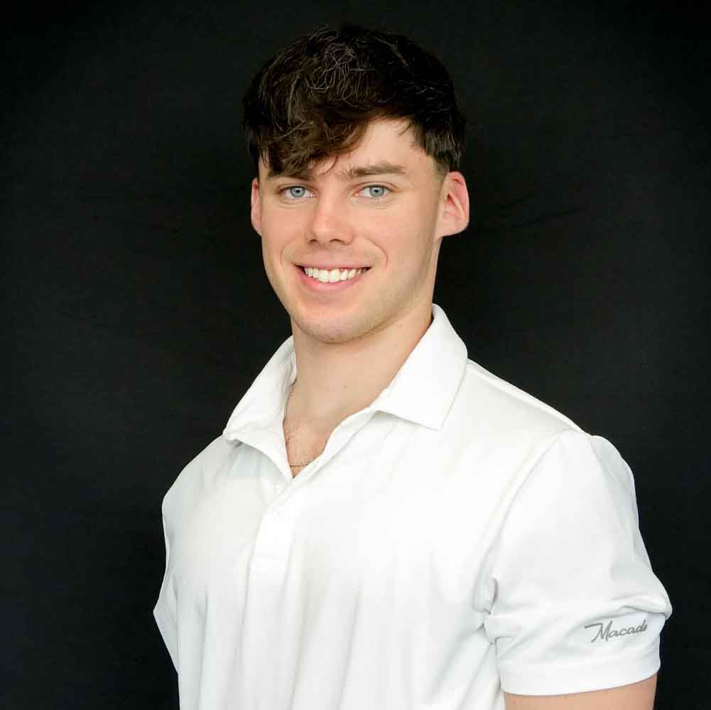 Image of a young man wearing a white polo smiling into the camera.
