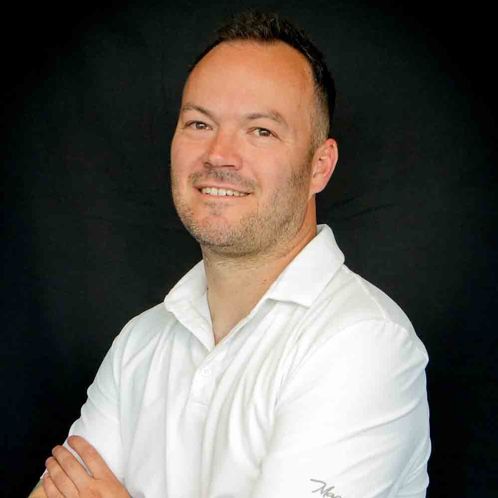 Image of a man wearing a white polo smiling into the camera.