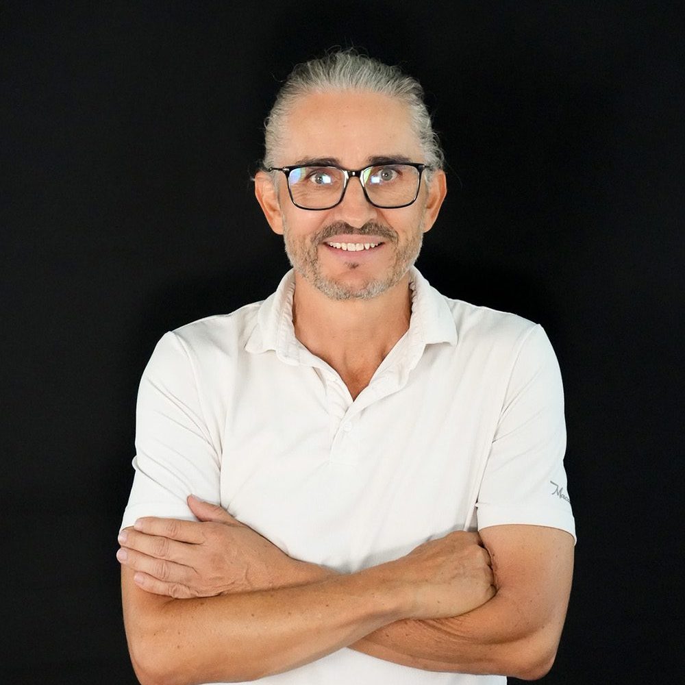 Image of a man wearing glasses and a white polo smiling into the camera.