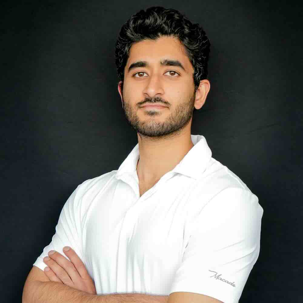 Image of a young man wearing a white polo smiling into the camera.