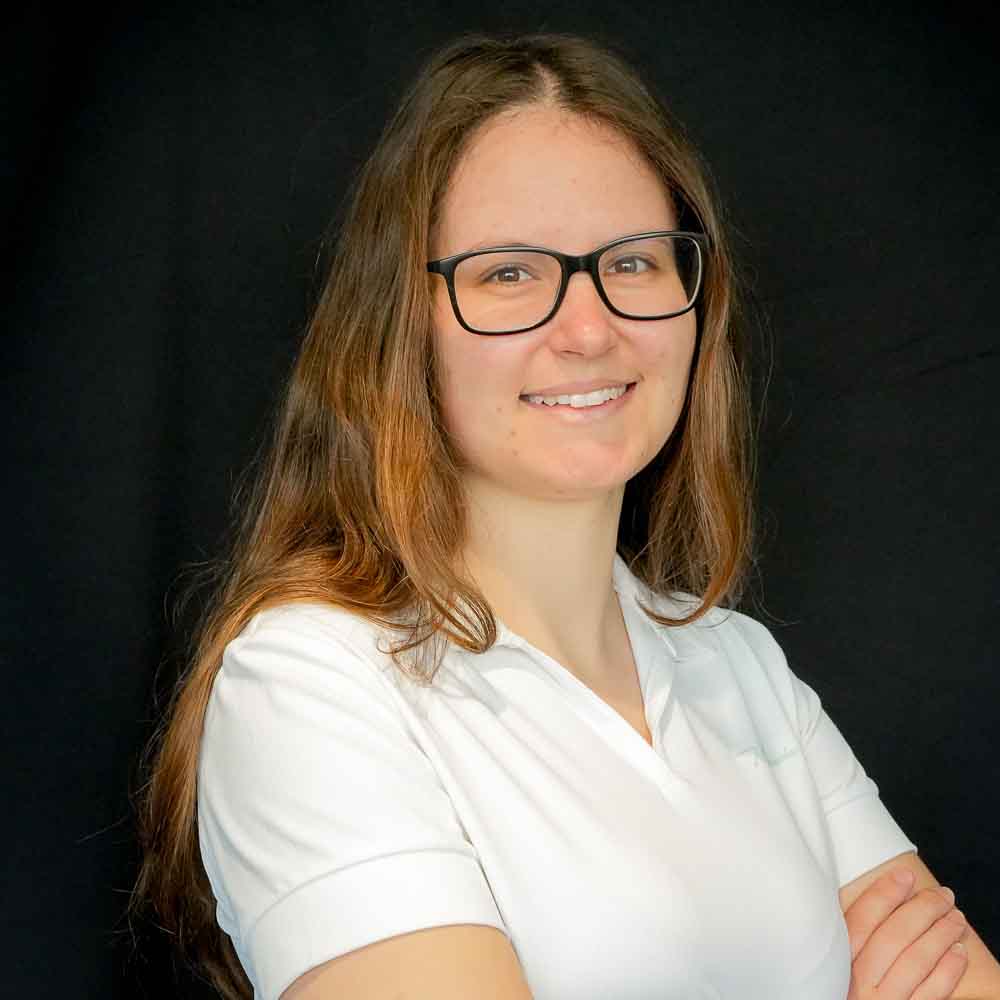 Image of a young woman wearing a white polo smiling into the camera.