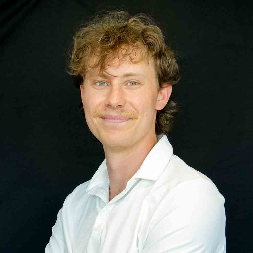 Image of a young man wearing a white polo smiling into the camera.