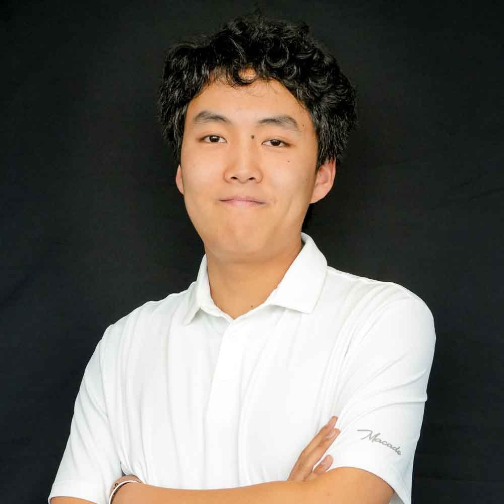 Image of a young man wearing a white polo smiling into the camera.