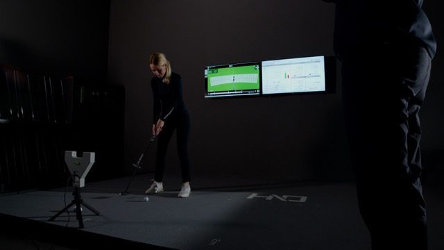 woman testing putter inside the HIO Fitting putting studio