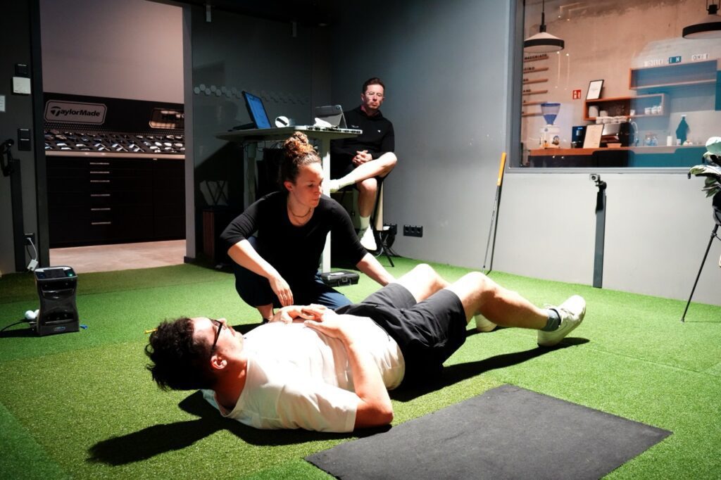 femaly phsio therapist treating a male golfer inside of a golf fitting studio
